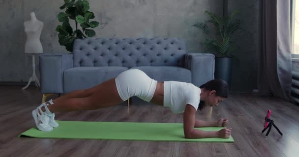 Sportig kvinna gör fitness och inspelning övningar på smartphone hemma. — Stockvideo