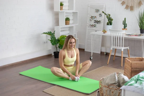 Woman doing sports at home watching video lessons on smartphone.