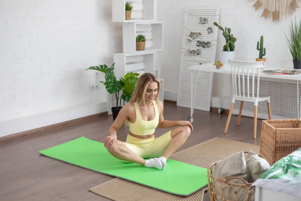 Woman doing sports at home watching video lessons on smartphone.