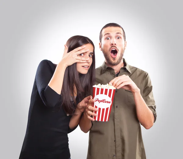 Jong koppel lettend op een film en eten popcorn — Stockfoto