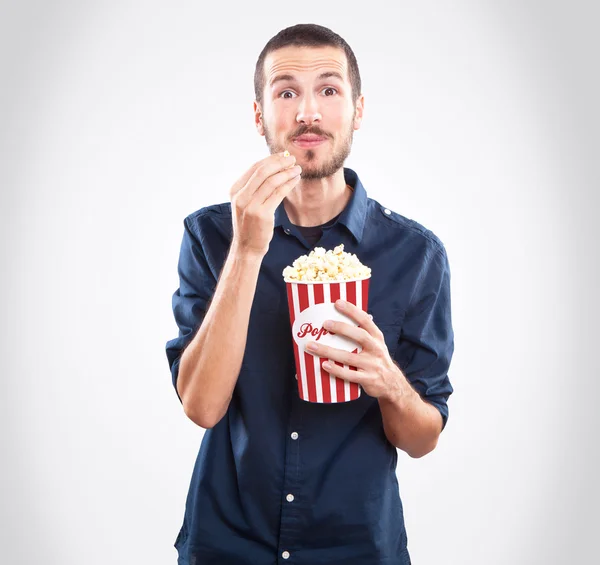 Ung man titta på en film och äta popcorn Royaltyfria Stockfoton