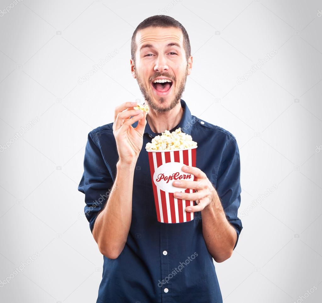 Young happy man watching movie and holding popcorn