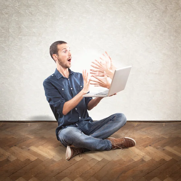 Young scared man holding a laptop — Stock Photo, Image