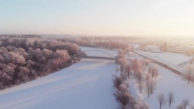 Gauja nehrinin havadan görünüşü, donmuş ağaçlar ve güneş doğarken üzerine köprü. Kış mevsimi. Letonya
