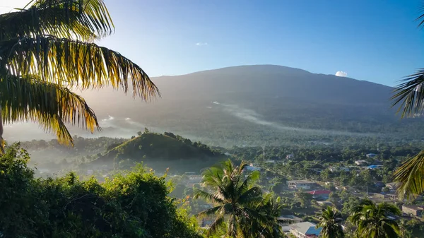 Panorama vista para a palmeira e aldeia em segundo plano na ilha de Grand Comoros durante o nascer do sol. Imagem De Stock