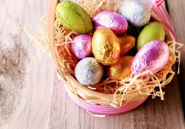 Colorful Easter eggs in straw basket — Stock Photo, Image