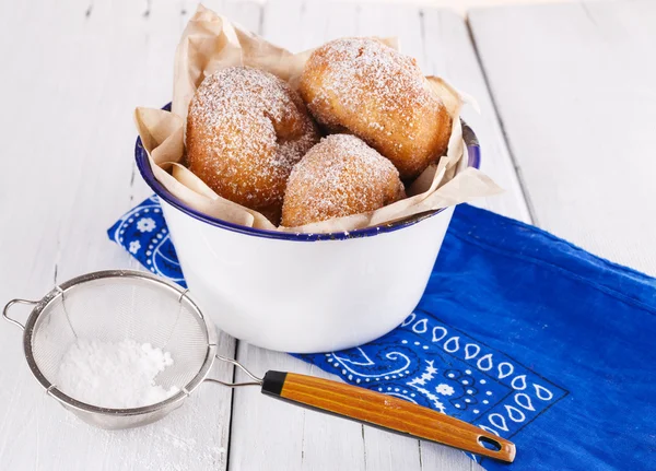 Sugar powdered cinnamon doughnuts in a metal rustic bowl on white wooden background with sieve  close up — Stock Photo, Image