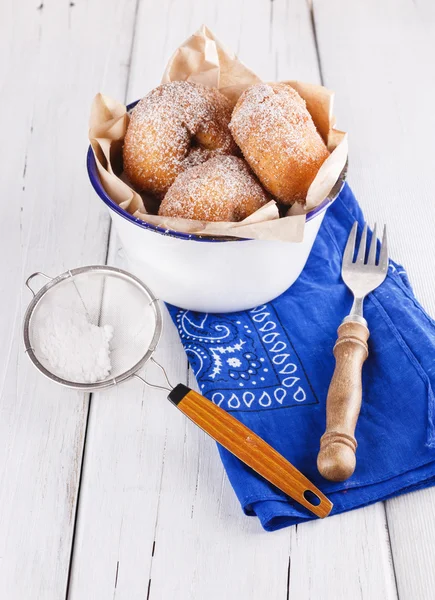 Sugar powdered cinnamon doughnuts in a metal rustic bowl on white wooden background with sieve and fork close up — Stock Photo, Image