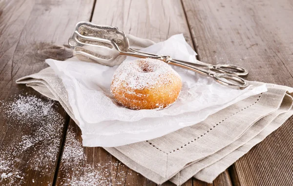 Sugar powdered cinnamon doughnuts on baking paper on rustic wooden background close up — Stock Photo, Image