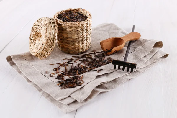 Black wild rice in a straw basket on a white wooden background — Stock Photo, Image