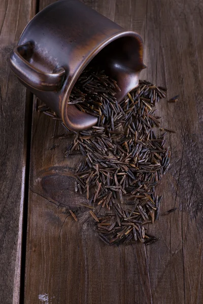 Black wild rice in a ceramic bowl on a rustic wooden background — Stock Photo, Image