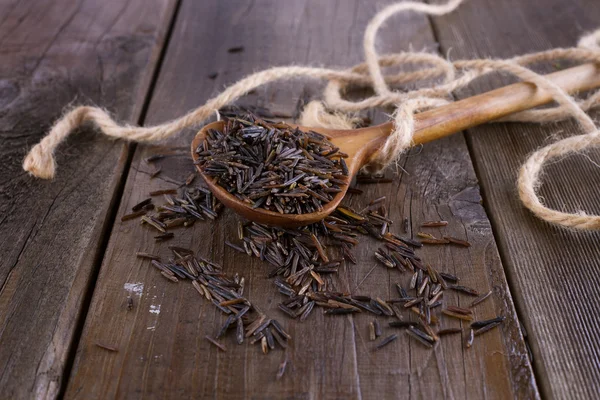 Zwarte wilde rijst in een houten lepel op een rustieke houten achtergrond — Stockfoto