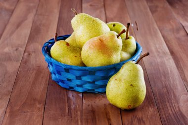 ahşap zemin üzerinde mavi dokuma sepet içinde organik armut