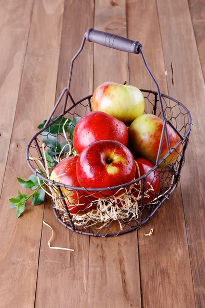 Maçãs orgânicas vermelhas em uma cesta de metal no fundo de madeira — Fotografia de Stock