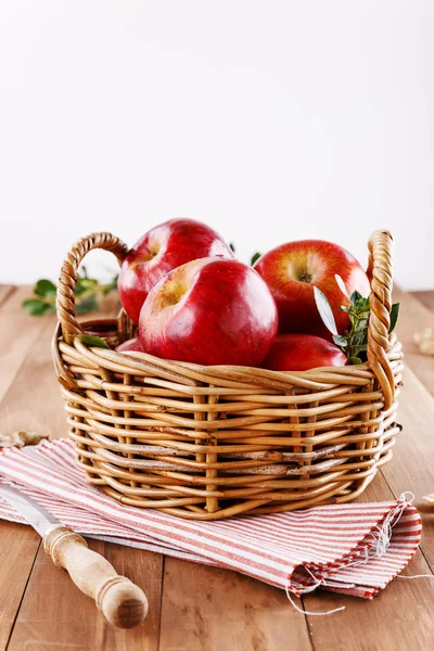 Manzanas rojas orgánicas en una canasta de paja sobre fondo de madera —  Fotos de Stock