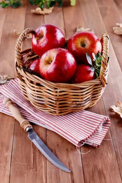 Red organic apples in a straw basket on wooden background — Stock Photo, Image