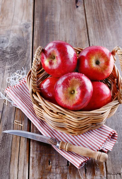 Manzanas rojas orgánicas en una canasta de paja sobre fondo de madera —  Fotos de Stock