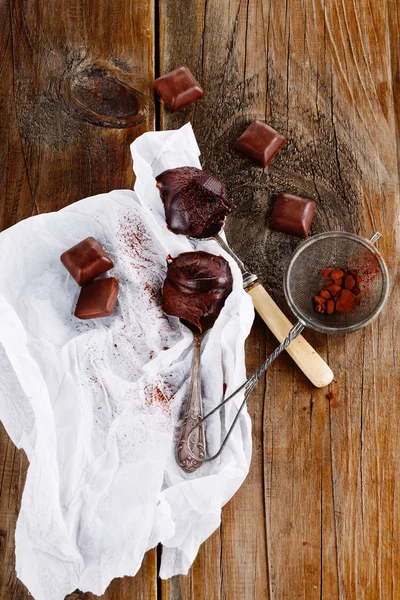 上铺的勺子和木制的背景上的黑巧克力的可可 — 图库照片