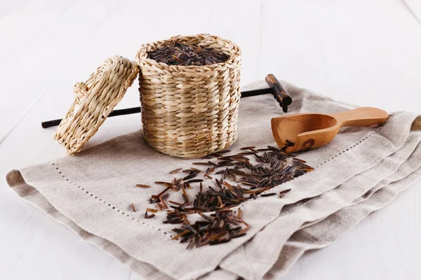 Arroz salvaje negro orgánico en una canasta de paja sobre un fondo de madera blanco — Foto de Stock