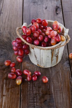 ahşap zemin üzerinde tahta bir kova kırmızı üzüm