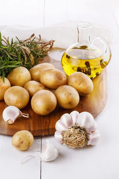 Rohe Bio-Kartoffel mit Rosmarin und Knoblauch über weißem Hintergrund — Stockfoto