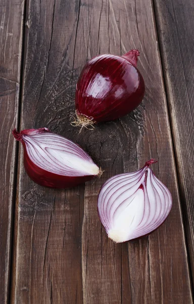 Cipolle rosse su uno sfondo di legno rustico — Foto Stock