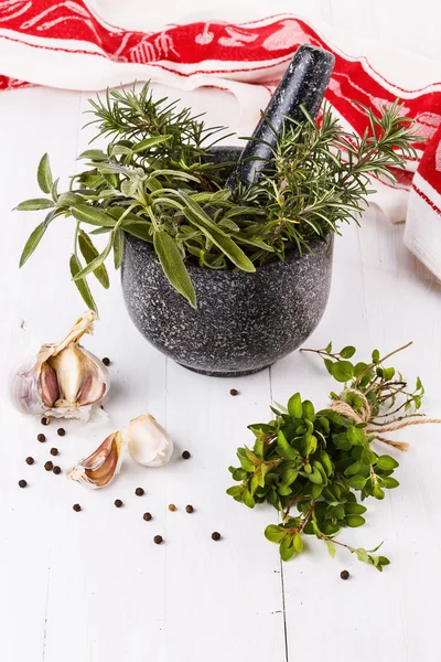 Fresh herbs in mortar over white wooden background — Stock Photo, Image