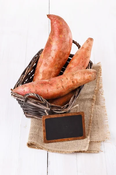 Cartofi dulci și etichetă peste fundal alb din lemn — Fotografie, imagine de stoc