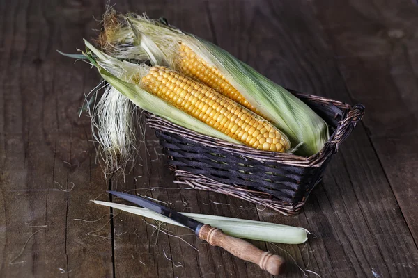 Sweet corns in a woven basket on rustic wooden background — Stock Photo, Image