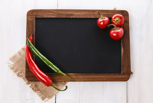Colorful chilli peppers on a black board — Stock Photo, Image