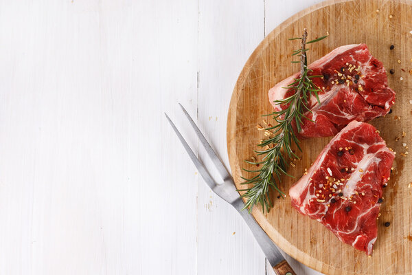 Red meat and rosemary over white background