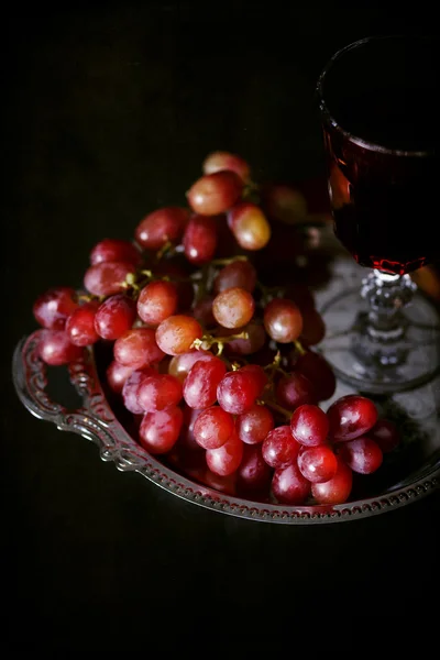 Vintage styl obrazem červených hroznů a sklenku vína — Stock fotografie