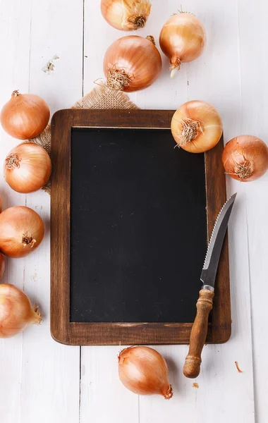 Cipolla marrone su uno sfondo di legno bianco — Foto Stock