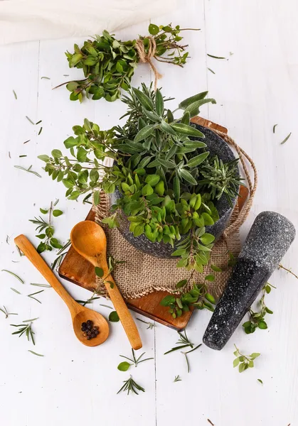 Fresh thyme and sage in mortar over white wooden background — Stock Photo, Image