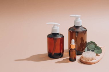 Doğal banyo malzemeleri seti - doğal organik kozmetik ürünleri olan cam damlaları, doğal yüz veya vücut kuru fırçası, okaliptüs yağı, krem, losyon, kahverengi arka planda gerekli yağlar. Model