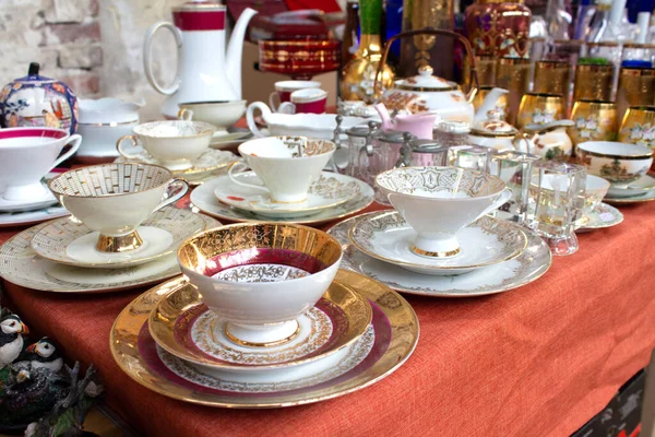 Antigüedades en el mercado de pulgas o festivales: tazas de té de porcelana vintage, vajilla y otras cosas vintage. Objetos coleccionables y concepto de venta de garaje. Enfoque selectivo, imagen tonificada —  Fotos de Stock