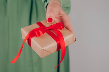 Kırmızı fiyonklu hediye kutusuyla süslenmiş kadınlar el ele tutuşur. Noel tatili, yeni yıl ya da doğum günü kutlaması konsepti. Noel için aile hediyeleri hazırlıyor, ona hediyeler hazırlıyor.