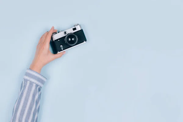 Eine weibliche Hand hält eine alte Vintage-Fotokamera auf hellblauem Hintergrund mit Kopierraum für Text. Trendige Vintage-Fotografie, Online-Fotografie Schulkonzept. Selektiver Fokus — Stockfoto
