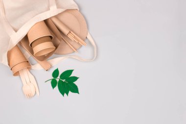 Çevre dostu sofra takımı - Kraft kağıt bardakları ve beyaz pamuk torbalarda açık gri arka planda fotokopi alanı olan kaplar. Sokak yemekleri kağıt ambalajı kaldırır. Bardaklar, tabaklar, pipetler. Seçici odak