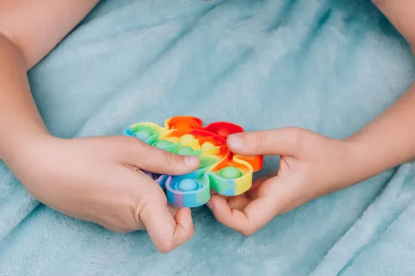 Gökkuşağıyla oynayan bir çocuğun yakın görüntüsü. Kıpır kıpır bir oyuncak. Serebral felçli çocuklar için Fidget sensör stres giderici oyuncak. Özel ihtiyaçları olan çocuklar için stres önleyici oyuncak