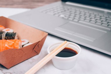 Farklı suşi ruloları, beyaz mermer masa zemininde beyaz mermer kutuda somon balığı, futomaki, uramaki ve hosomaki. Çevrimiçi sipariş yiyecek ve dağıtım konsepti. Seçici odak