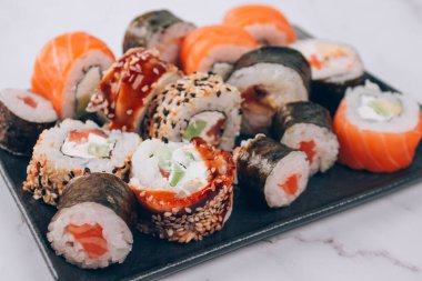 Suşi bar öğle yemeği menüsü. Somon, avokado ve önlüklü suşi ruloları beyaz mermer masa üzerinde fotokopi alanı - futomaki. uramaki, maki. İnternetten yemek sipariş et, yemek götür.