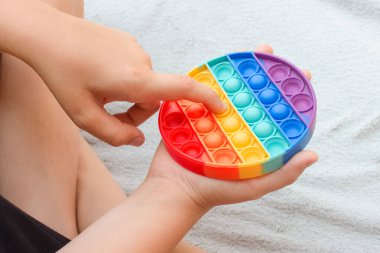 Çocuk gökkuşağıyla oynuyor pop it kıpır kıpır oyuncak. Kabarcık hareketli duyusal silikon stres atma oyuncağı. Stres önleyici oyuncak. Çocuk akıl sağlığı konsepti