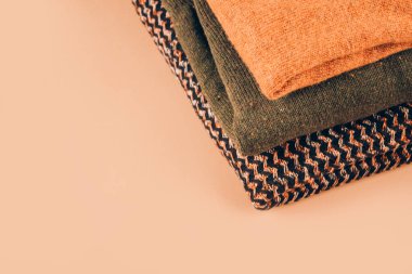 Sonbahar ya da kış süveteri yığını. Bej arka planda fotokopi alanı var. Kıyafet bağışları, bilinçli ve çevre dostu konsorsiyum - alışverişte yeni trendler, yavaş moda konsepti