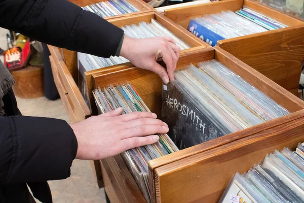 Lviv, Ukrayna - 7 Mart 2021: Bit pazarından veya garaj satışından vinil plak alan adam. İçinde retro vinil bekarlar plakları olan tahta kutular. Seçici odak