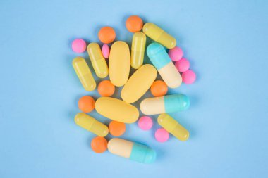 Bağışıklık sistemi vitaminleri ve takviyeleri çeşitliliği. Beslenme biyo takviyeleri. Mavi arka planda çok renkli ilaç hapları, kapsüller ve tabletler var.