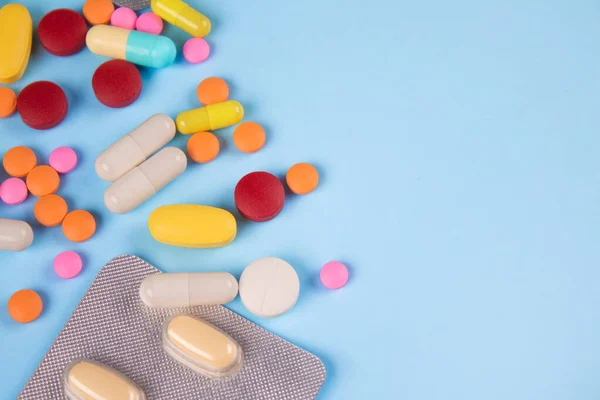 Close up view of assorted multicolored medicine pills, capsules and tablets on blue background with copy space for your text. Immune system vitamins and supplemets. Dietary bio supplements — Foto Stock