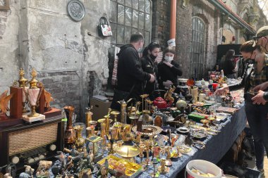 Lviv, Ukrayna - 16 Mayıs 2021: Lem İstasyonu 'nda garaj satışında maske takan insanlar. Bit pazarında hippi eskitilmiş mallar. Ucuz alışveriş, yeniden kullanılabilir konsept. Klasik yemekler ve dekor.