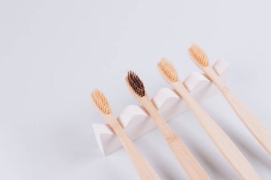 Biege alçı kalıbının üzerindeki doğal bambu diş fırçalarının gri arka planda fotokopi alanı ile üst görünümü. Sürdürülebilir yaşam tarzı, sıfır atık ev. Seçici odaklanma. Model resmi
