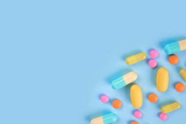 Assorted medicine pills, capsules and tablets on blue background with copy space. Immune system vitamins and supplemets. Selective focus, flat lay